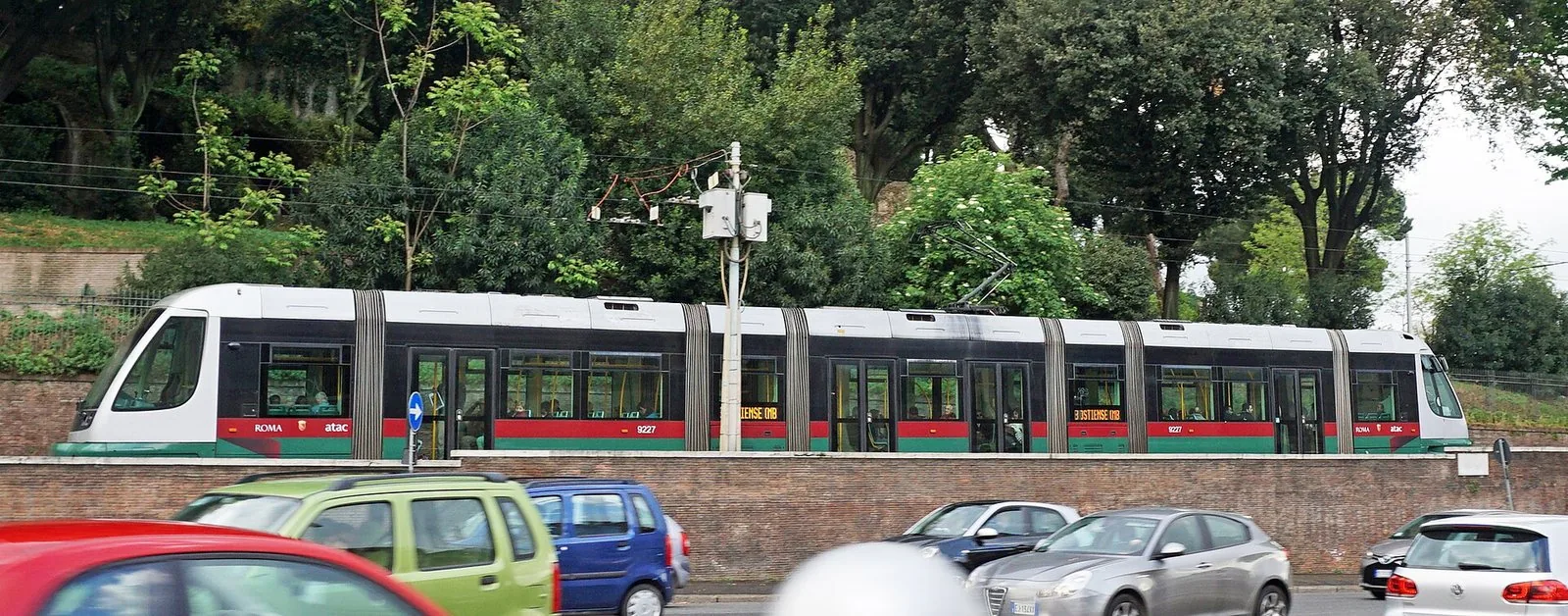 Un tram della rete di Roma in transito su una strada alberata